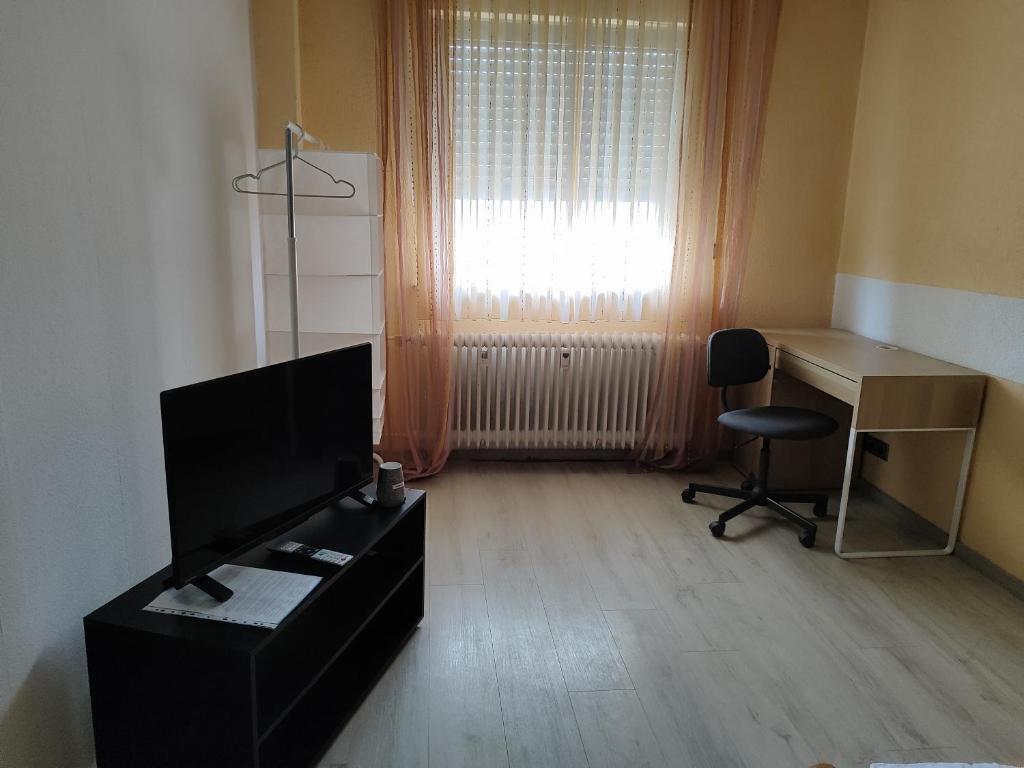 a living room with a desk and a television at Ferienwohnung Belvie 3 in Butzbach