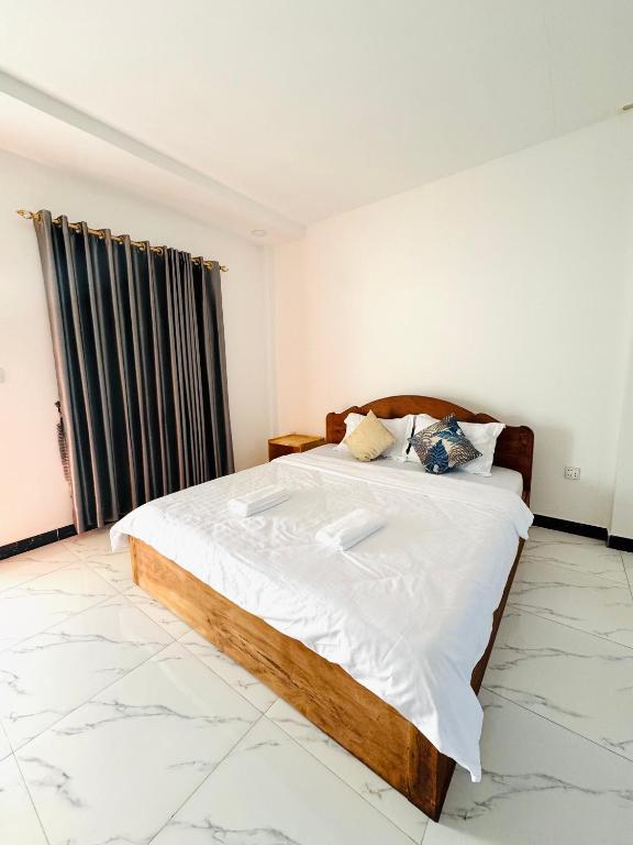 a bedroom with a large bed with white sheets at BM guest house in Phnom Penh