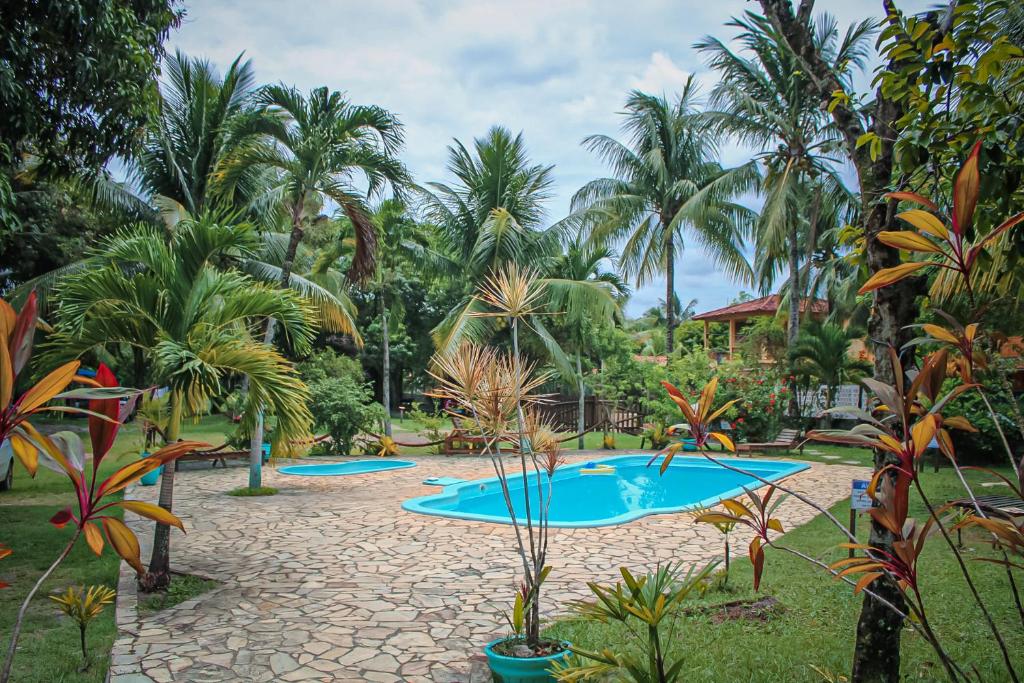 a resort with a pool and palm trees at Pousada Sargi&mar in Uruçuca