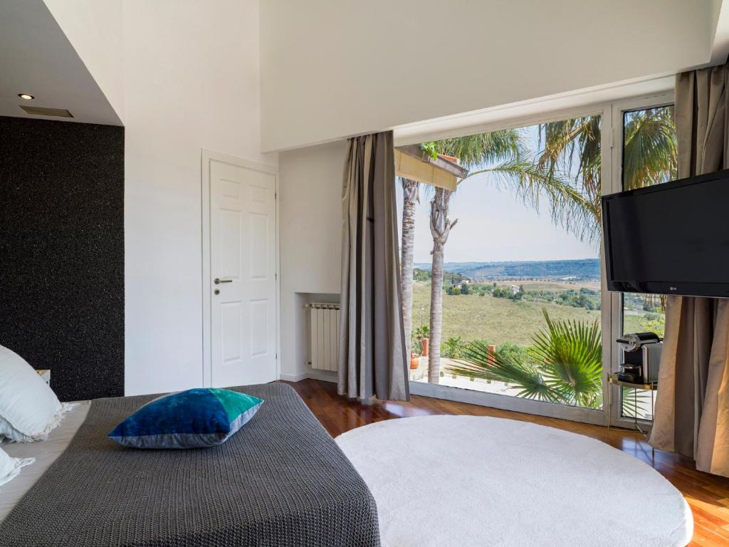 a bedroom with a bed and a large window with a view at Villa Nunziatina in Carlentini