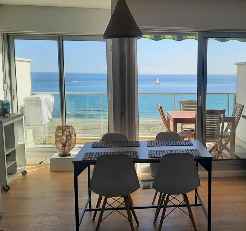 una mesa y sillas en una habitación con vistas al océano en Happy 7, en Canet-en-Roussillon