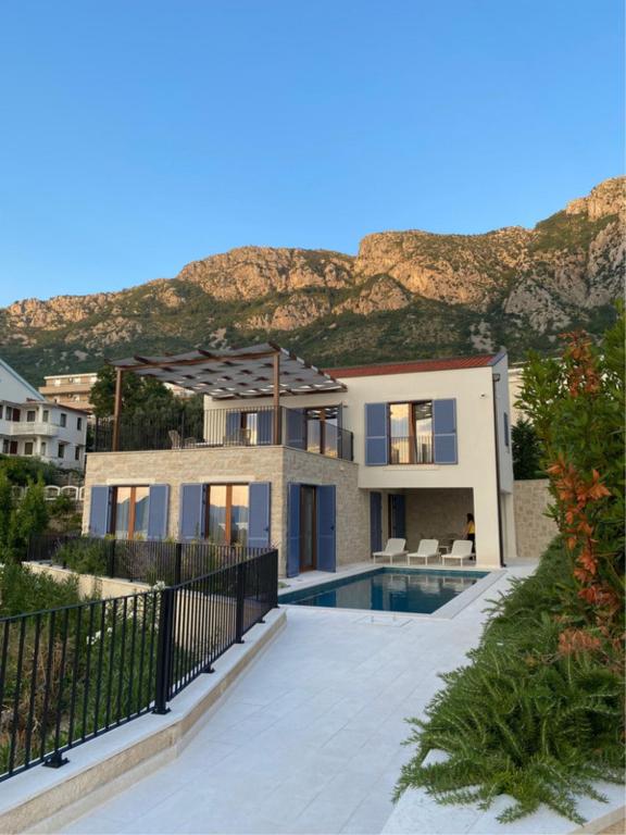 ein Haus mit einem Pool vor einem Berg in der Unterkunft Belsize Villas in Budva