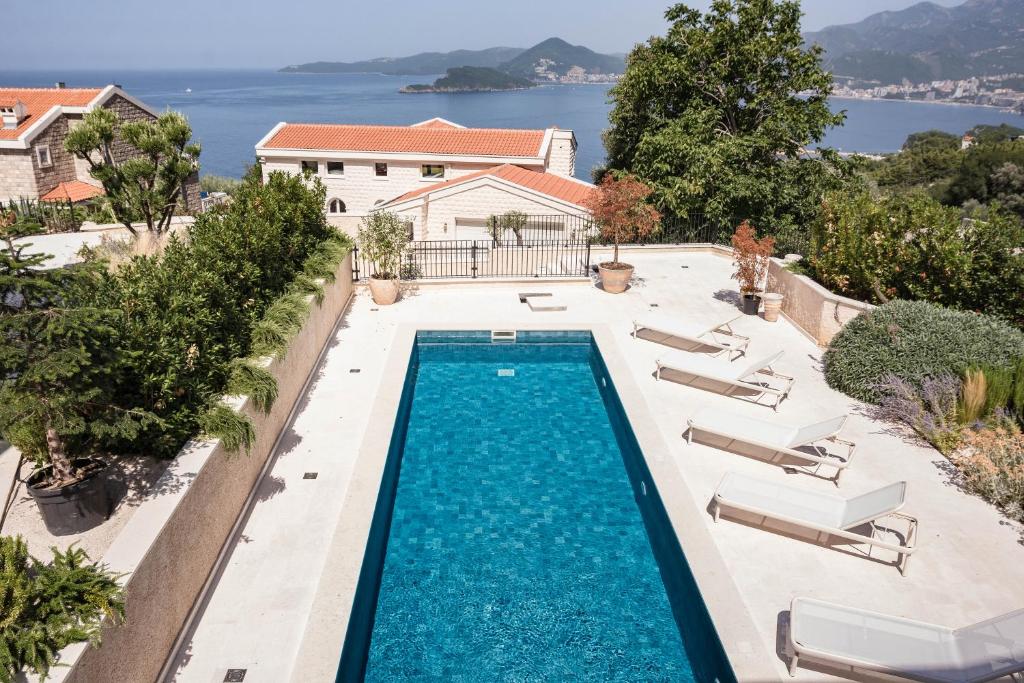 Bild eines Swimmingpools mit Stühlen und eines Hauses in der Unterkunft Belsize Villas in Budva