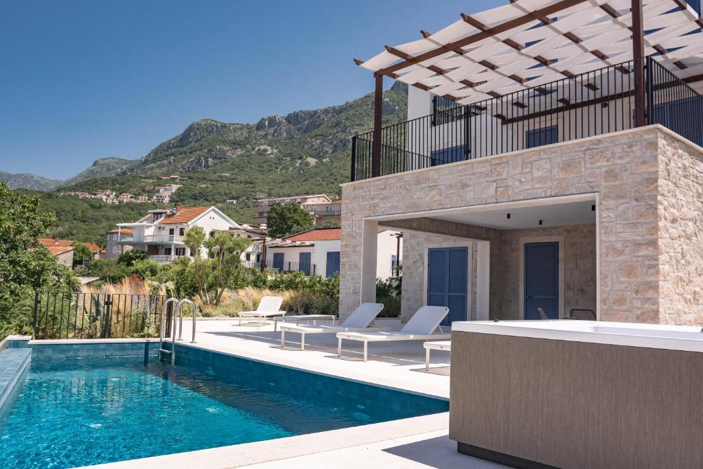 eine Villa mit Swimmingpool mit Bergen im Hintergrund in der Unterkunft Belsize Villas in Budva