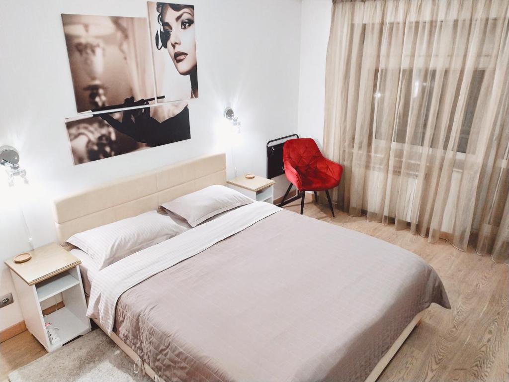 een slaapkamer met een bed en een rode stoel bij Luxury apartment in the heart of the capital in Kiev