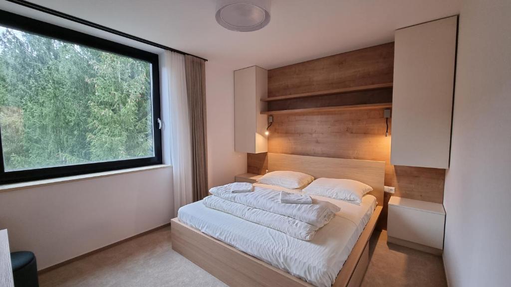 a bedroom with a bed with a large window at Chalets Hrabovo in Ružomberok