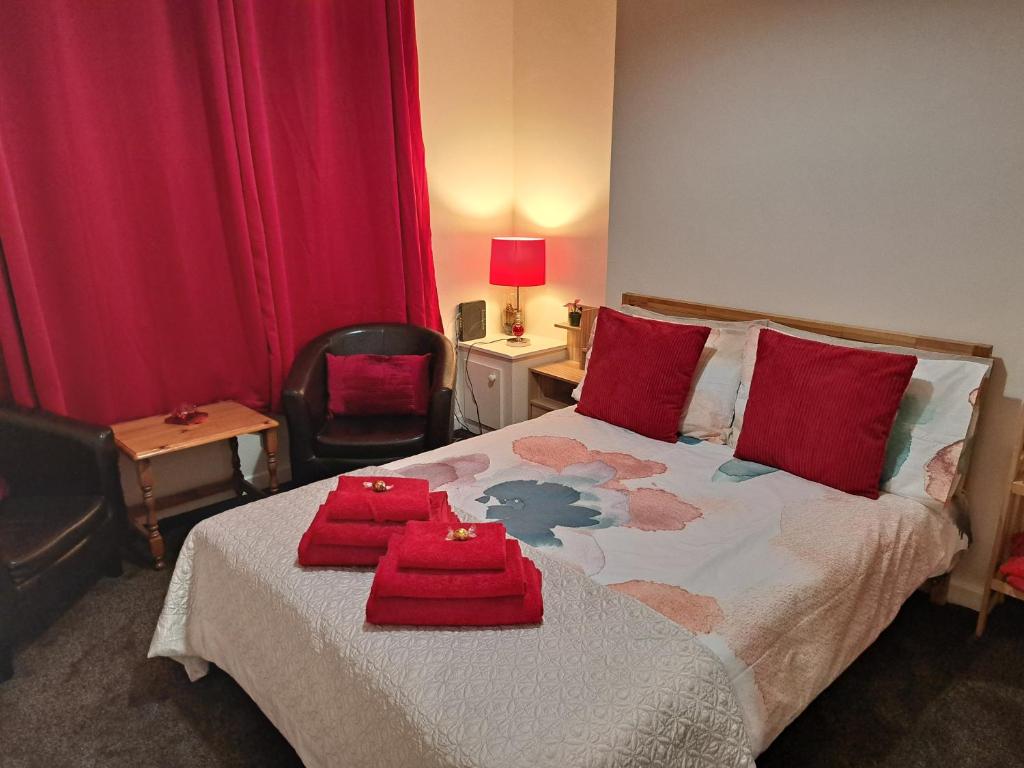 ein Schlafzimmer mit einem Bett mit roten Kissen darauf in der Unterkunft Nina's Cozy Lodge in Wigan