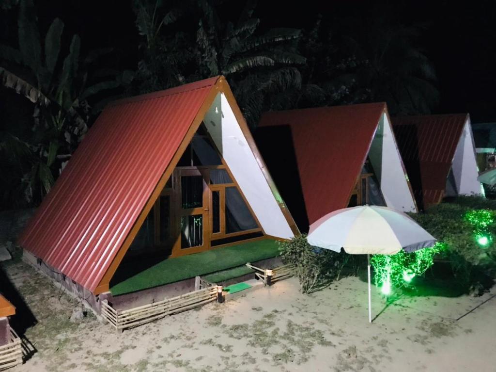 una pequeña casa con techo rojo y sombrilla en Changmai's Inn, en Kāziranga