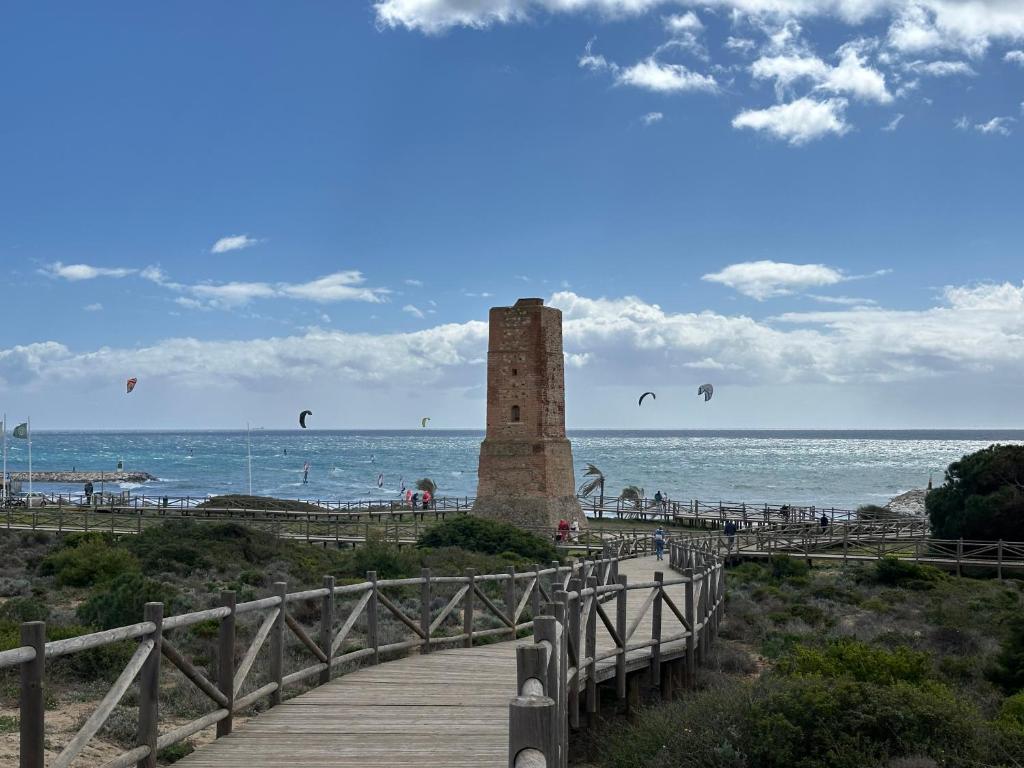 ein Leuchtturm am Strand mit Drachenfliegen in der Unterkunft Piso en Marbella cerca de la playa in Marbella