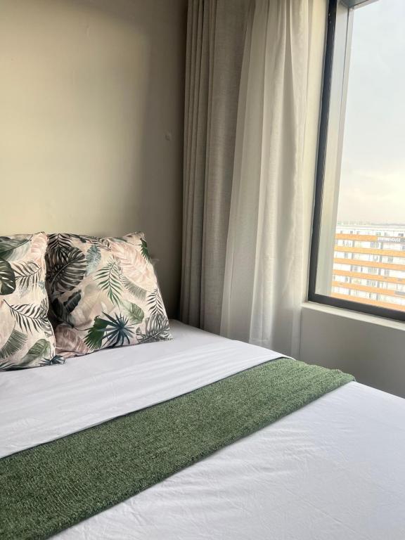 a bed with a pillow and a window at The onyx in Johannesburg