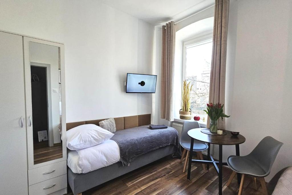1 dormitorio con cama, mesa y ventana en Pomorska86 Aparts - Łódź Centrum, en Łódź