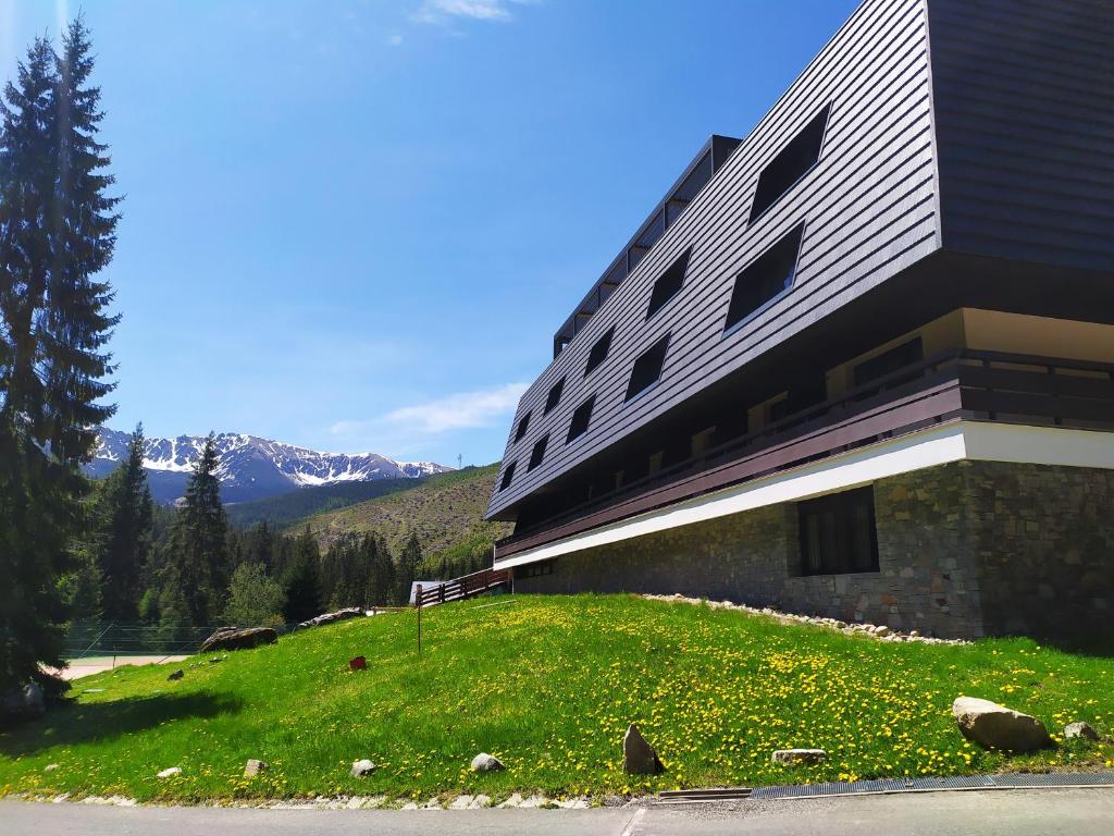 un edificio en la cima de una colina con césped en Wellness Hotel Repiska en Demanovska Dolina