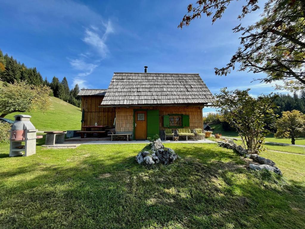 a small cabin in a grassy field with a tree at Chalet Hike&Bike above Bohinj valley in Bohinj