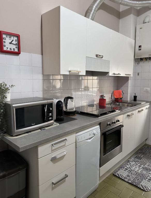 a kitchen with white cabinets and a microwave at Monolocale Comodo alla Metro in Turin
