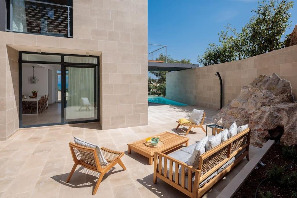 a patio with a couch and chairs and a table at 5-star modern stone villa Sea La Vie in Sutivan