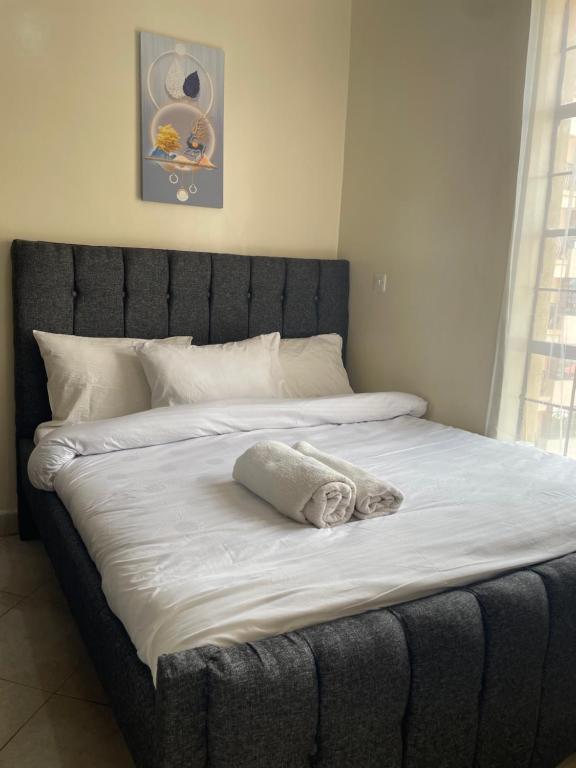 a bed with a gray headboard with a towel on it at SNOWHAVEN BnB Kitengela in Kitengela 