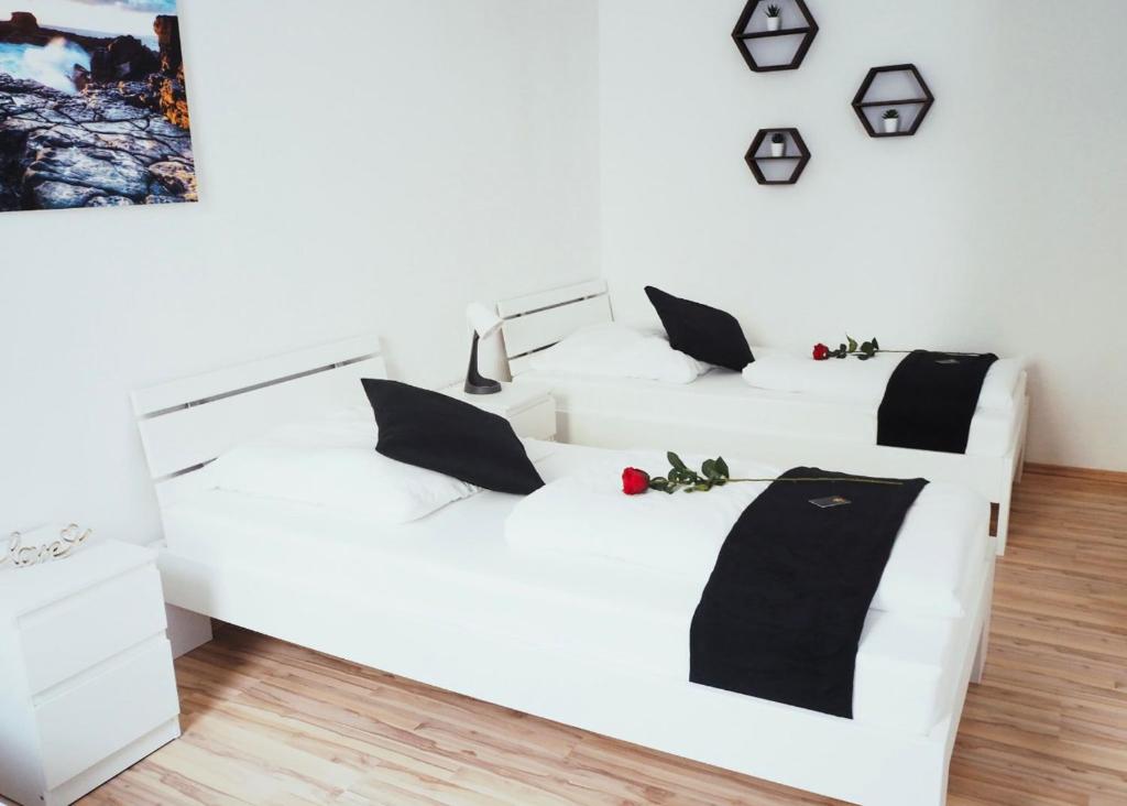 2 witte bedden met zwarte kussens in een kamer bij NÜRNBERG Monteurwohnung in Neurenberg