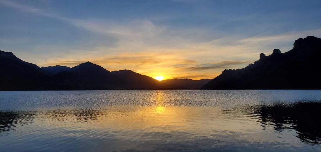 un coucher de soleil sur un lac avec des montagnes en arrière-plan dans l'établissement La Torre del Lago, à Villa Meliquina