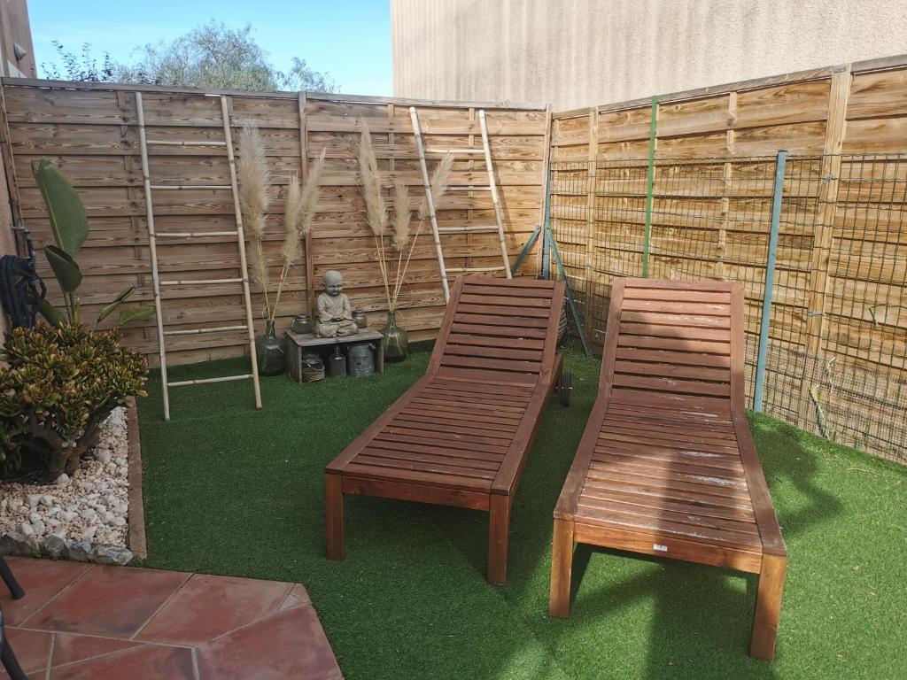 - deux chaises en bois et un banc dans le jardin dans l'établissement Maison Cosy 6 couchages à 700 mètres de la plage, à Torreilles