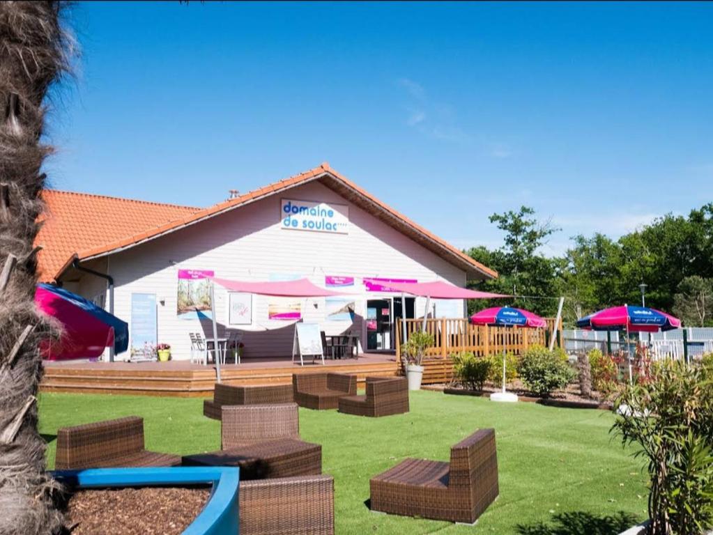 a house with a yard with benches and umbrellas at MH camping 4 étoile Mer/forêt in Soulac-sur-Mer