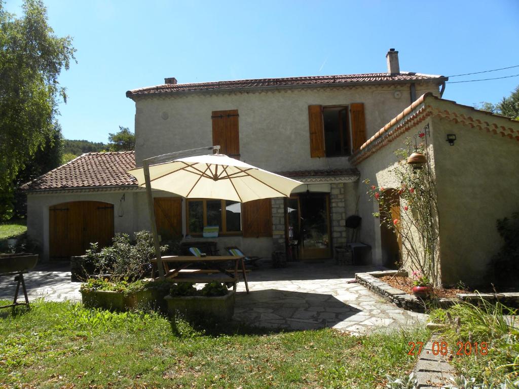 a table with an umbrella in front of a house at Domaine de Pré Rond in La Faurie
