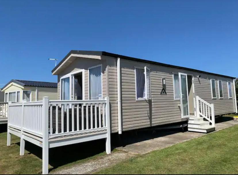 a mobile home with a porch and a white railing at Immaculate 2020 Caravan on Newquay Holiday Park in Newquay