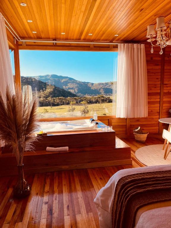 a bedroom with a large window with a view at Romantic Getaway with Jacuzzi and Breakfast in Rancho Queimado in Rancho Queimado