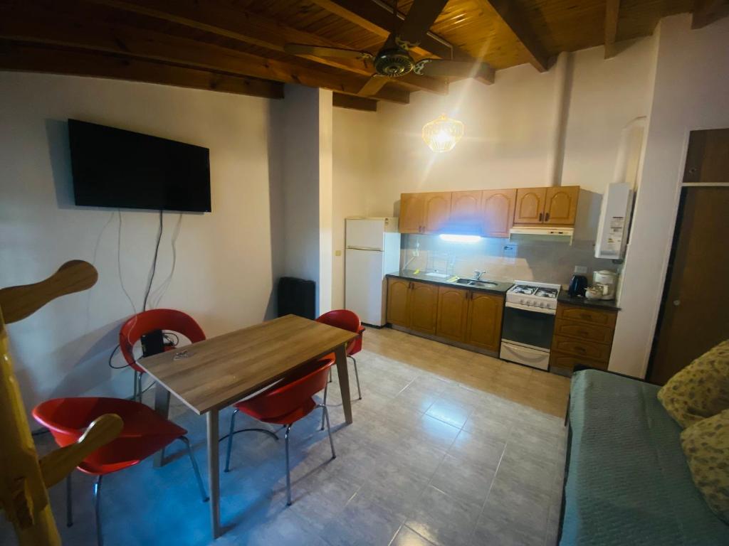 eine Küche mit einem Holztisch und roten Stühlen in der Unterkunft Cerquita de Shopping: depto amoblado urbano in Neuquén