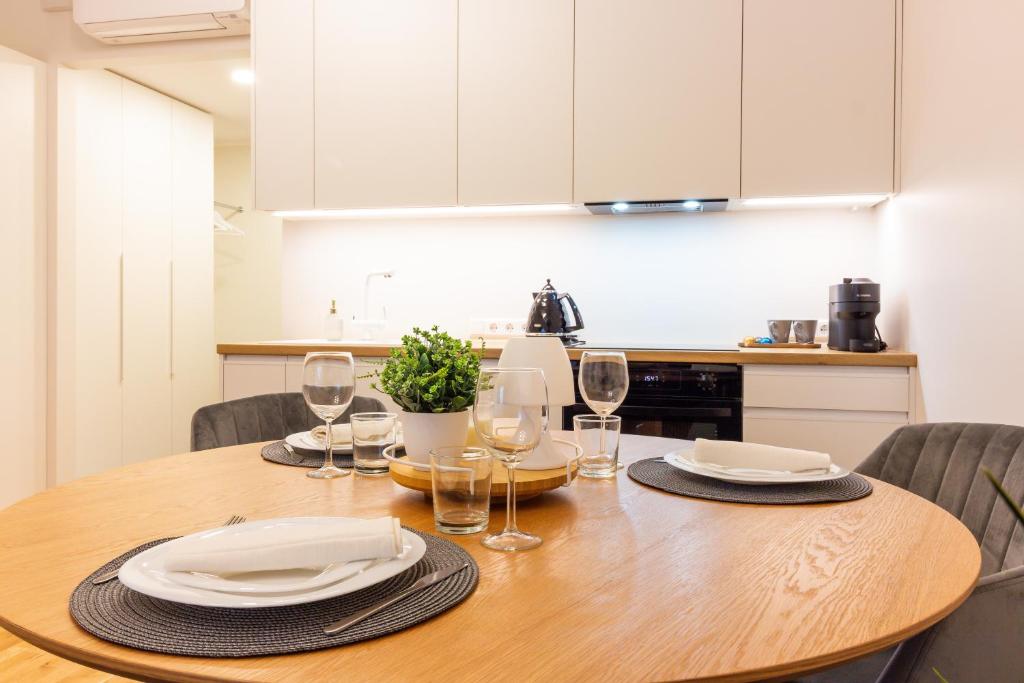 - une table en bois avec des assiettes et des verres à vin dans l'établissement Riia 22 Kesklinna Apartment, à Tartu