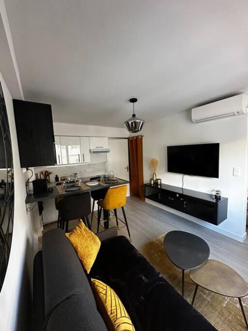 un salon avec un canapé et une table avec des chaises dans l'établissement Joli F2, 7 min de la gare, à Cannes