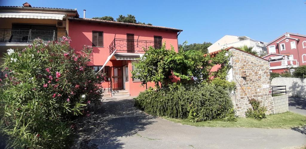 ein rosa Haus mit Blumen davor in der Unterkunft Hišica na morju in Ankaran