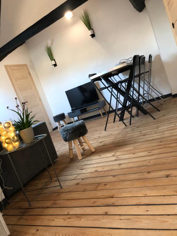 Una sala de estar con un televisor y una mesa y sillas. en Appartement Art moderne entre Disney et Paris, en Lagny