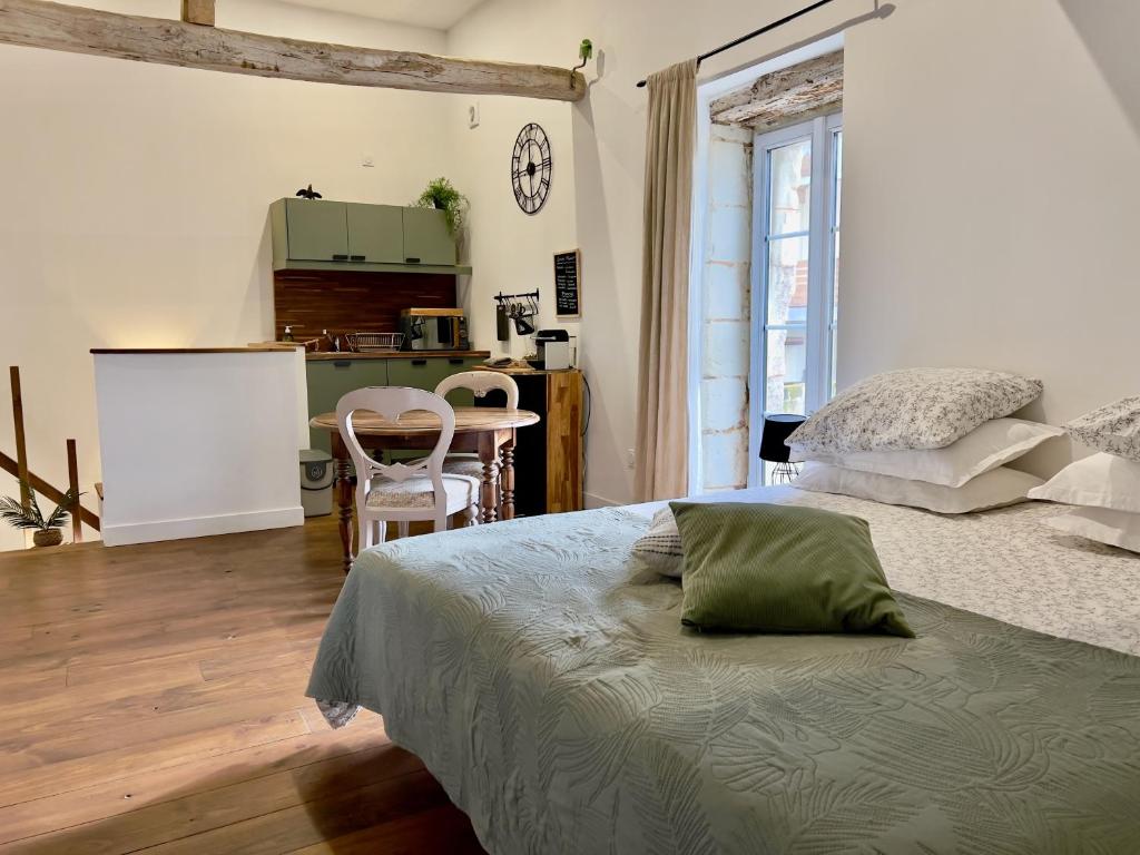 a bedroom with a bed and a table and a kitchen at Studio la Grange in Fontevraud-l'Abbaye