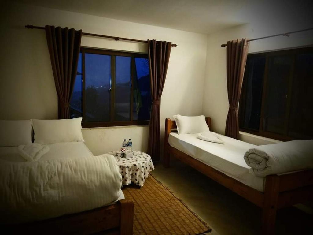a bedroom with two beds and a window at Hotel Gogreen Kattike Pvt. Ltd. in Nagarkot