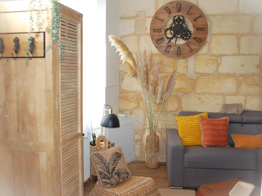 ein Wohnzimmer mit einem Sofa und einer Uhr an der Wand in der Unterkunft Authentique échoppe bordelaise in Libourne
