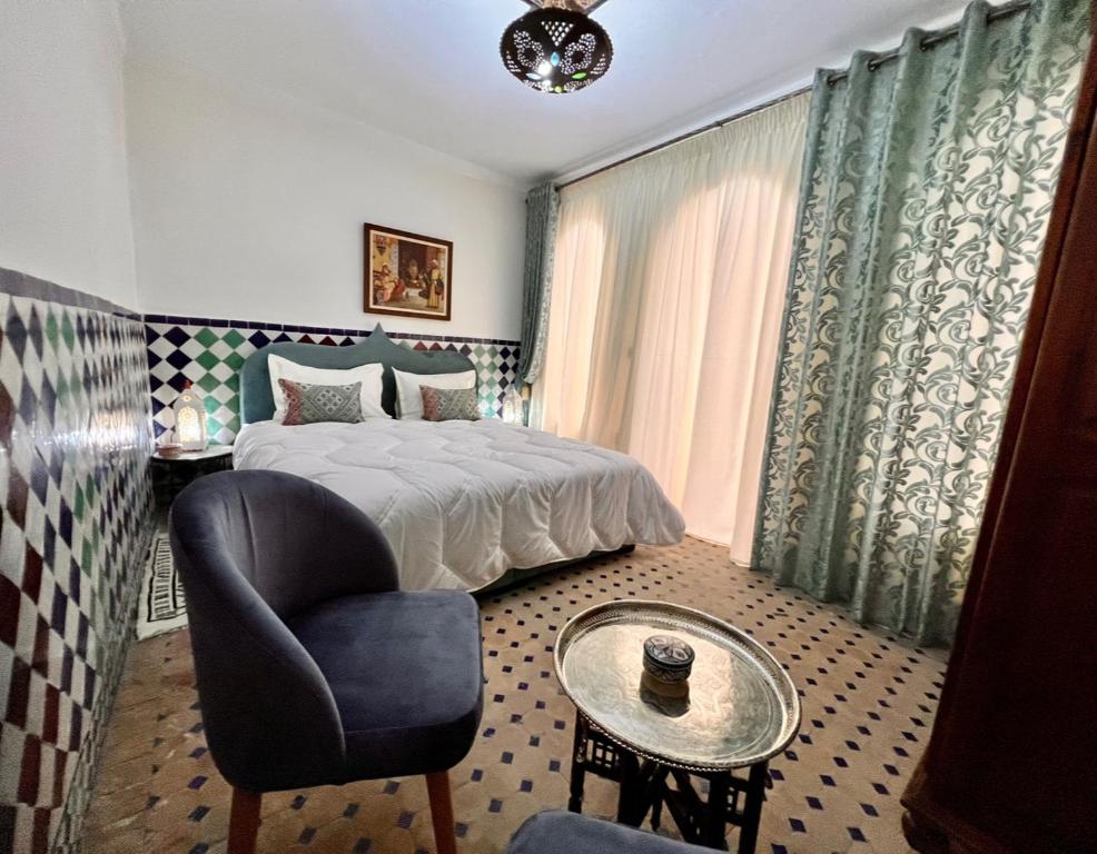 a bedroom with a bed and a chair and a table at Riad de charme - la perle des Oudayas in Rabat