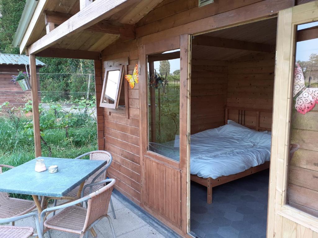 1 cama en una casa de madera con mesa en Wijndomein de Vier Ambachten -overnachten in de wijngaard, en Simonshaven