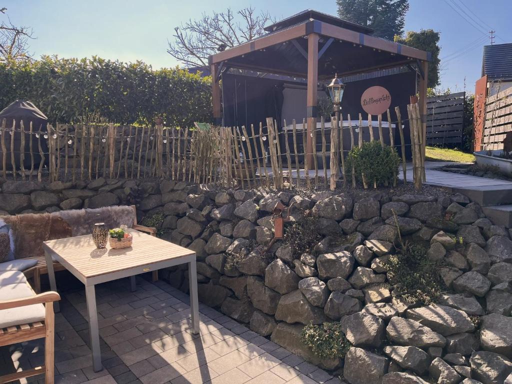 pared de piedra con mesa y edificio en Eifelferienhaus An der Kapelle - kostenlose Sauna, Ofen en Kerschenbach