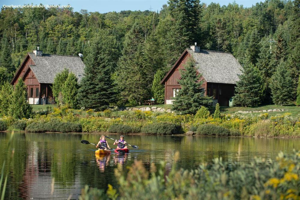 two people kayaking on a river in front of a house at Royal Laurentien in Saint-Faustin