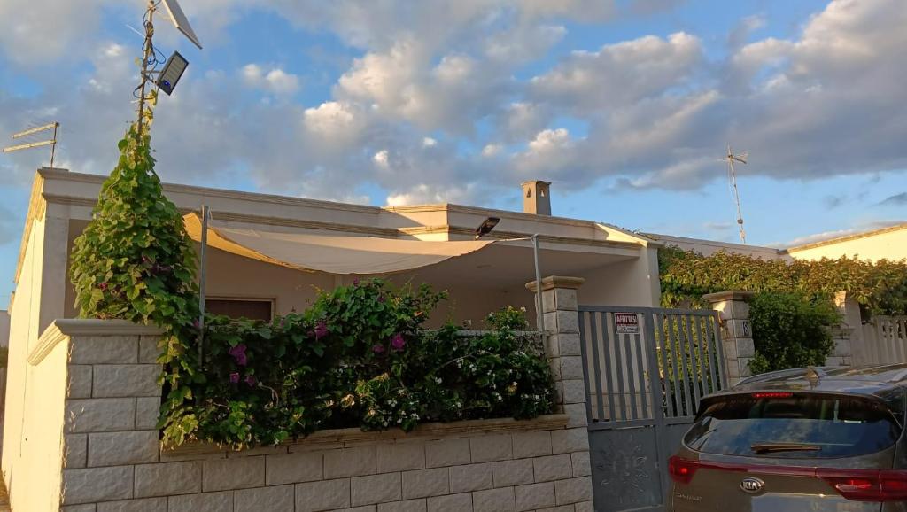 a house with a fence and a car parked in front of it at Casa Totò - Punta Prosciutto Apartment in Punta Prosciutto