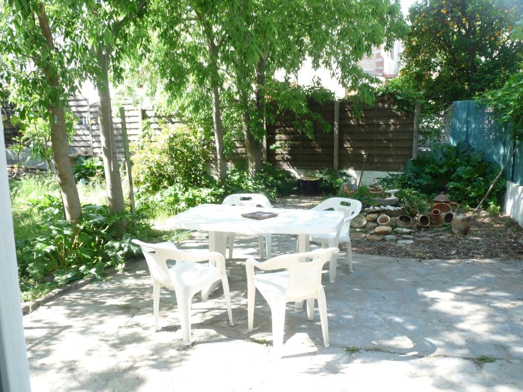 une table et des chaises blanches dans une cour arborée dans l'établissement a l'ombre des micocouliers, à Sorède