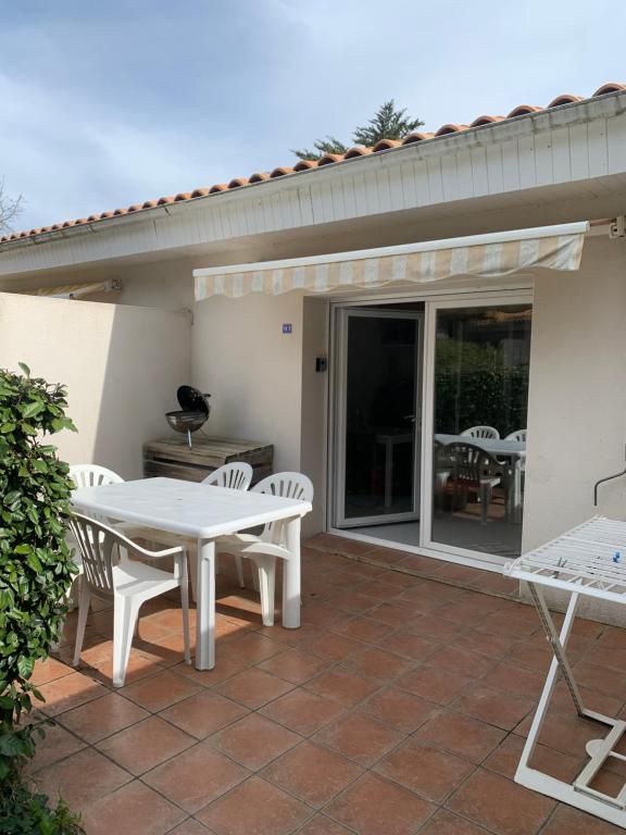 a patio with a white table and chairs on a patio at Maisonnette Mimosa H3 avec piscine intérieure chauffée à 400 m de la plage et ménage de fin de séjour compris in Les Sables Vignier