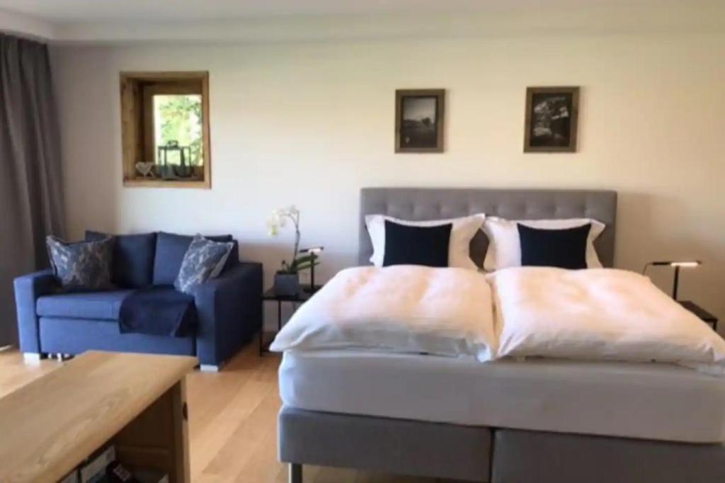 ein Schlafzimmer mit einem Bett und einer blauen Couch in der Unterkunft Haus Hochland - Moderne Alpenwohnung Garten&Natur in Bad Kohlgrub