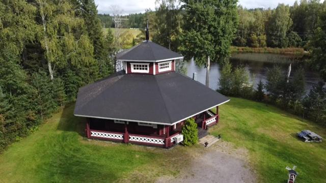 uma casa com um telhado preto num campo verde em Karhunhovi em Pääjärvi