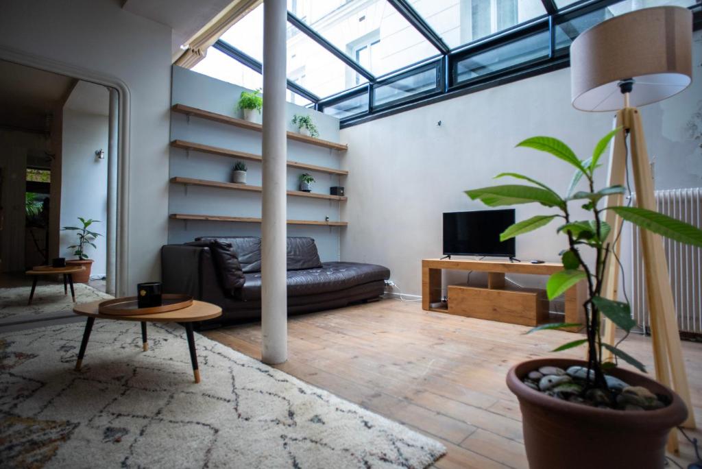 ein Wohnzimmer mit einem schwarzen Sofa und einem TV in der Unterkunft Loft branché dans le quartier le plus tendance de Paris in Paris