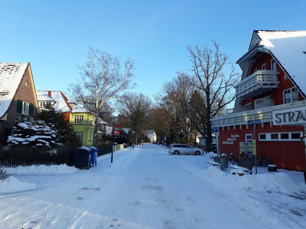eine schneebedeckte Straße mit einem roten Gebäude in der Unterkunft Ferienwohnung Strandstraße, Haberland in Müritz