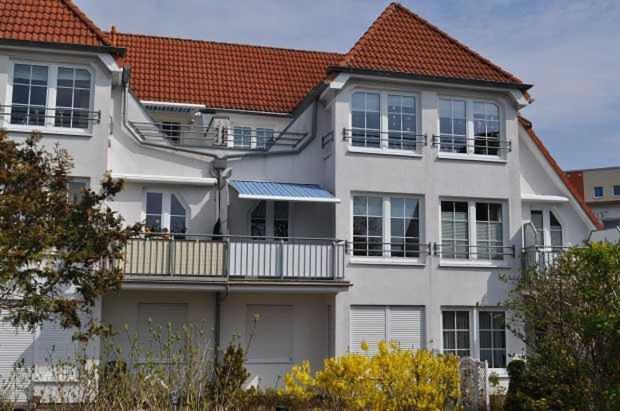 a white house with a balcony on the side of it at FeWo Möwennest Felstehausen GM 69252 in Graal-Müritz