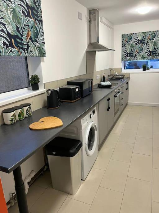 eine Küche mit einer Theke und einer Waschmaschine in der Unterkunft Affordable Newly Refurbished 3 Bedroom House, Sleeps 7, NG8 Postcode in Nottingham
