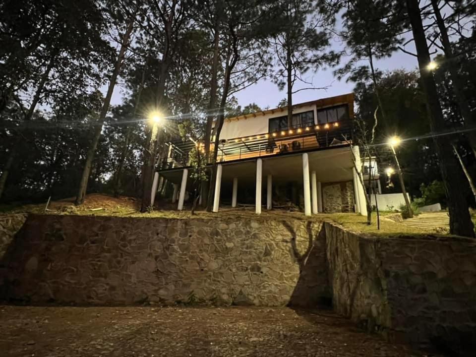 une maison au sommet d'un mur de pierre la nuit dans l'établissement Cabaña Veinte 21, à Mazamitla