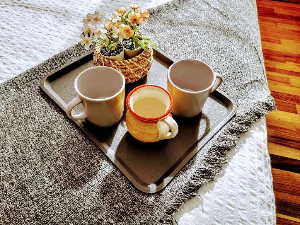 a tray with two coffee mugs and a basket of flowers at Apartamento Portugalete Gran Bilbao 3 dormitorios - 3 bedrooms in Portugalete